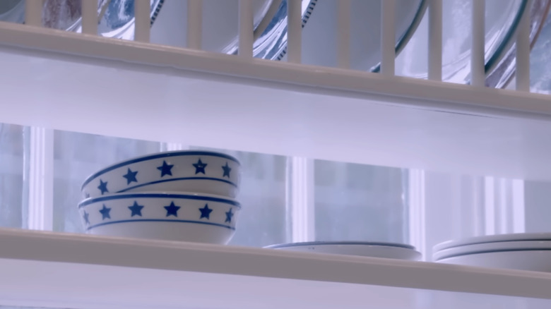 A white plate rack in front of a kitchen window