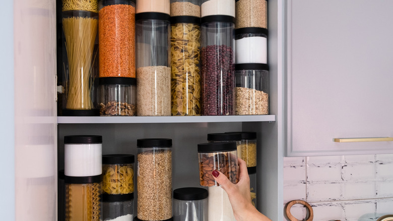 hand holding a container of snacks being put back in the pantry