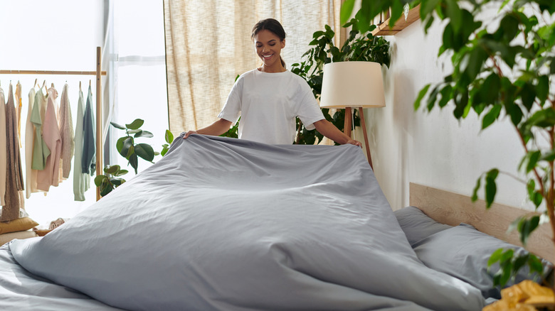 A woman changing the sheets on a bed