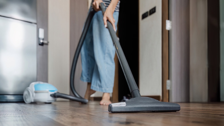 A person vacuuming a hardwood floor