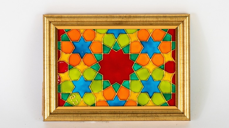 A handmade stained glass arrangement in a picture frame, hung on a white wall