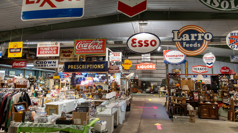 The interior of a thrift store with lots of vintage signs hanging from the ceiling