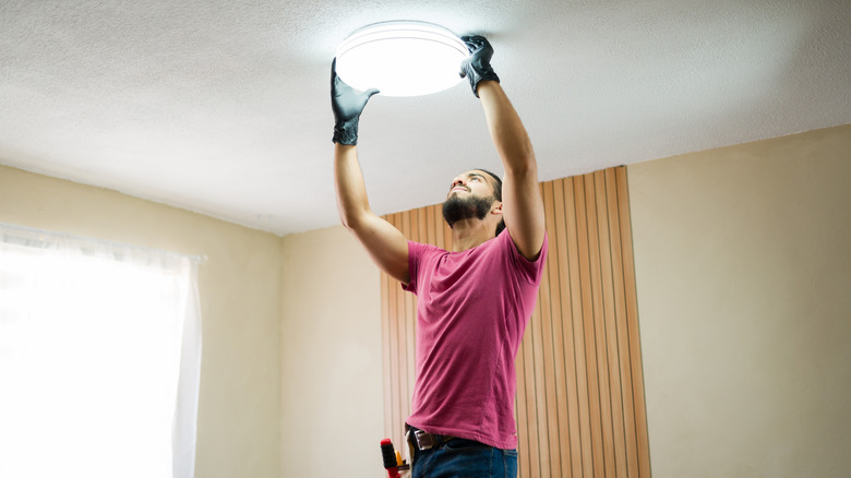 A contractor installing a light fixture