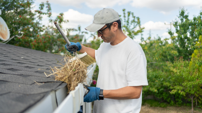 A person clearing straw from a gutter
