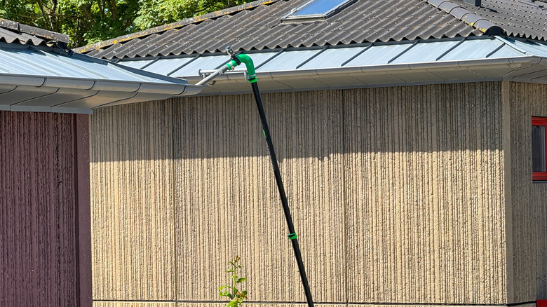 A gutter being cleaned with a long-reach vacuum wand