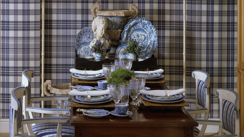 A dining room set with plaid wallpaper in the background.