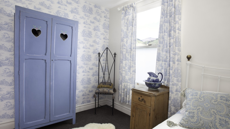 A small room with toile de jouy wallpaper and matching curtains.