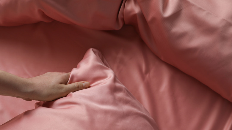 Hand holding the edge of pink silk sheet