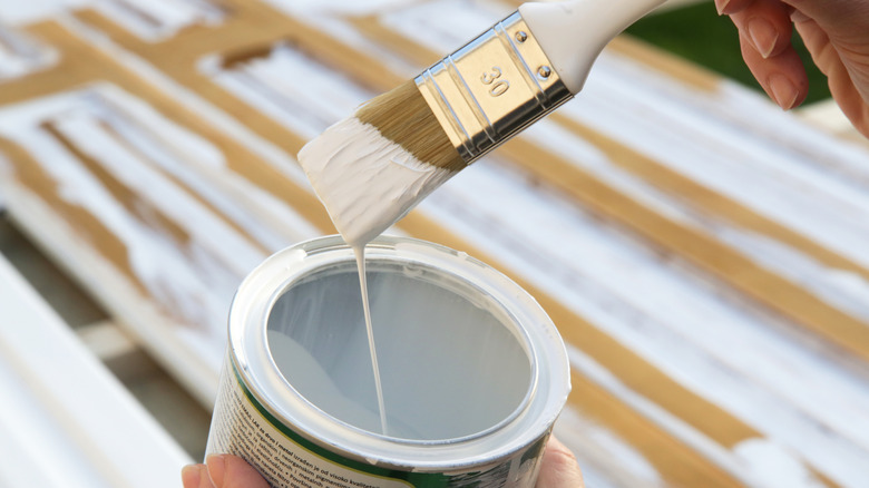 Close-up of a painter dipping a paintbrush in a tin of paint