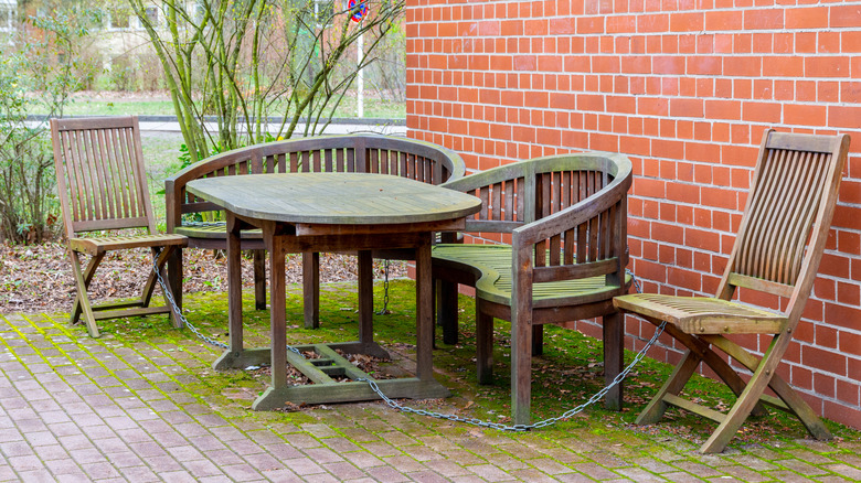 A set of wooden garden furniture, covered in green algae
