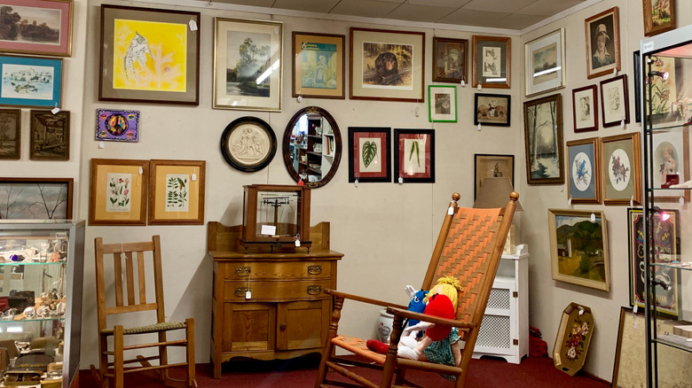 A thrift store wall fill of artwork, prints, and mirrors.