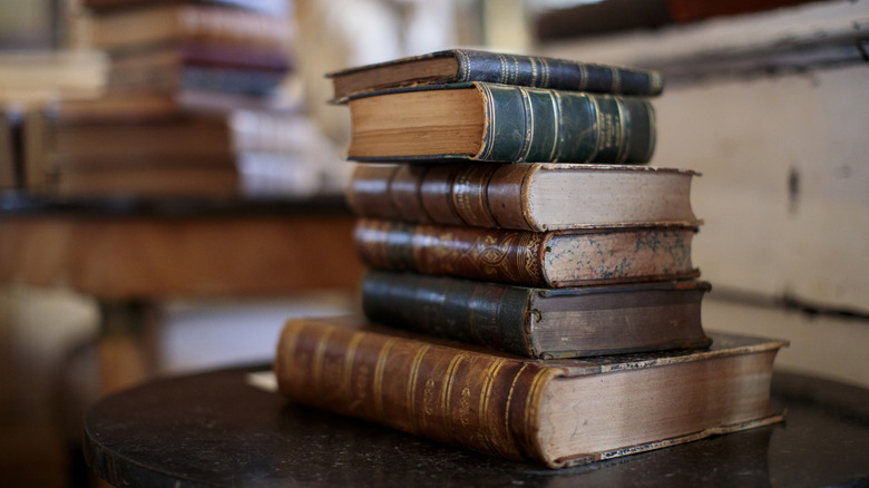 A stack of various colored vintage books worn with use