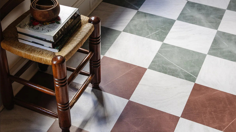 A wicker chair on muted green and red checkered floors.