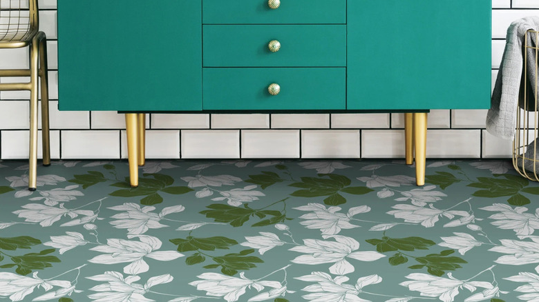 A teal dresser and a blue and green floral patterned floor.