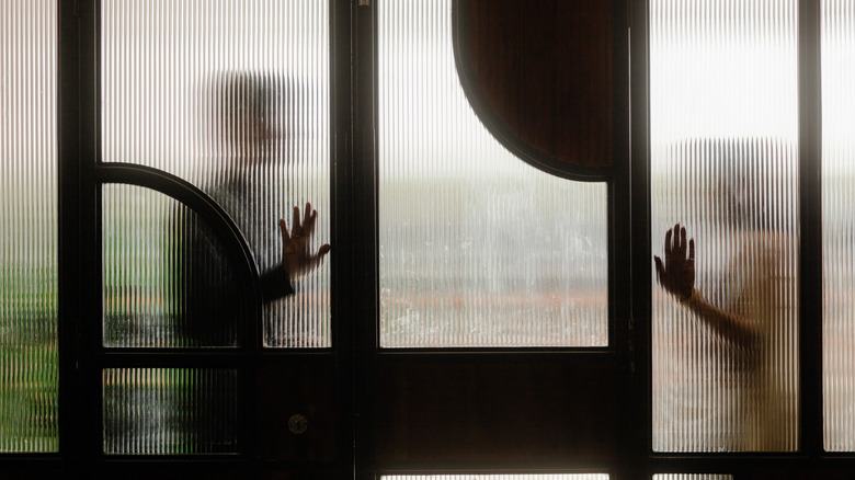 Silhouettes behind a reeded glass wall.