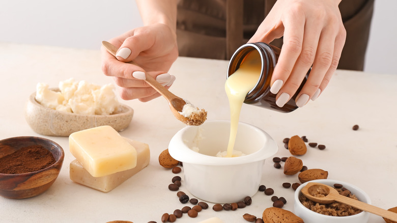 A woman's hands are shown mixing soap ingredients together, with finished soap and ingredients nearby