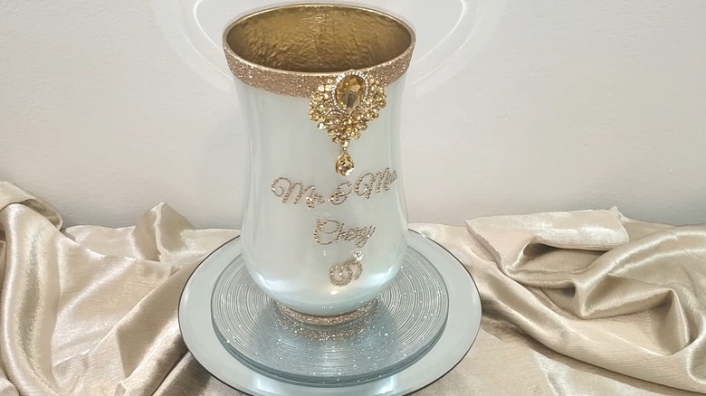 Vase painted and decorated with glitter and gemstones sitting on a tray