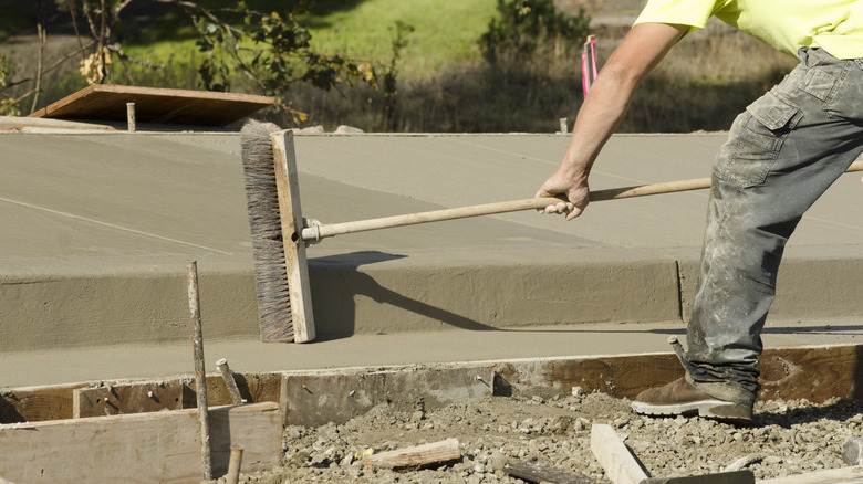 A man creating a broom finish texture on a driveway.