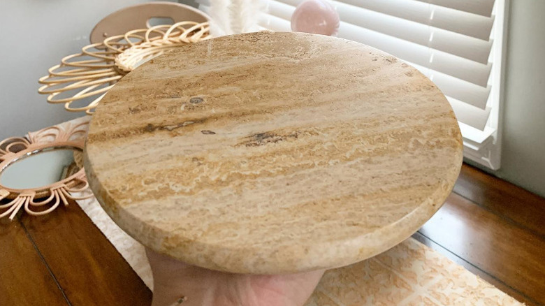 hand holding sandy colored stone trivet