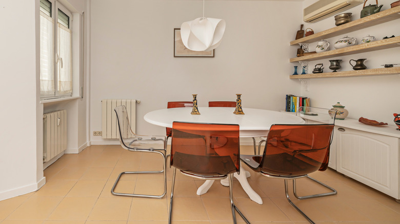A dining room at sunset with a large wooden table, eight chairs, and a sputnik chandelier