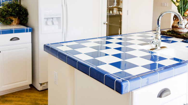 A kitchen island with blue and white tiles.