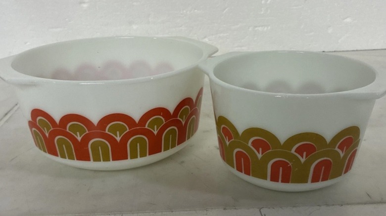 Two straight sided white Pyrex bowls decorated with gold and orange arches