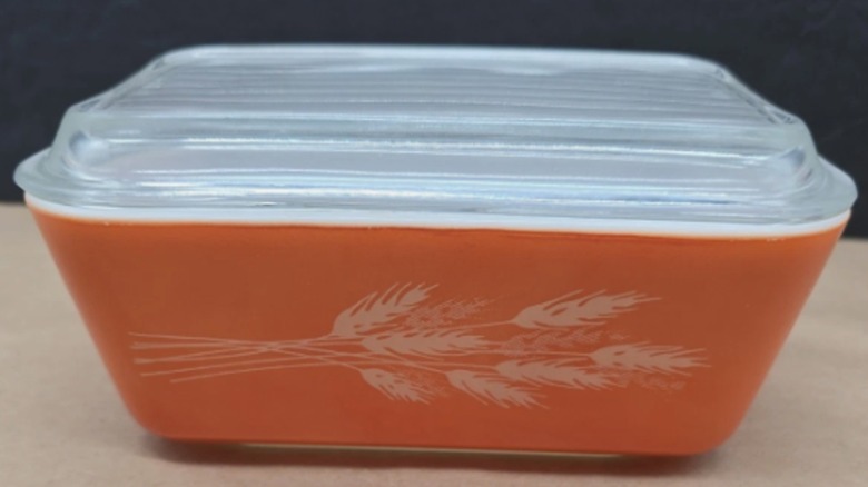 An orange Autumn Harvest Pyrex butter dish with a glass lid