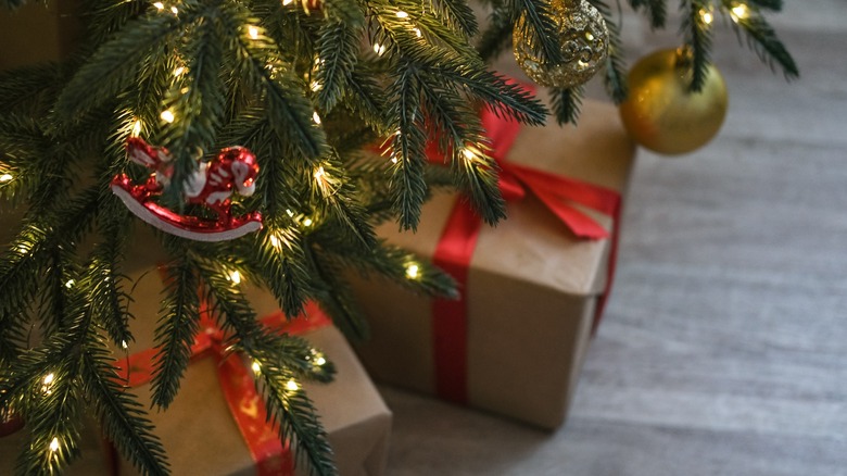 Gifts under a Christmas tree wrapped in brown paper with red ribbons