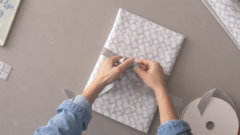 Woman tying a bow around a present wrapped in shelf liner