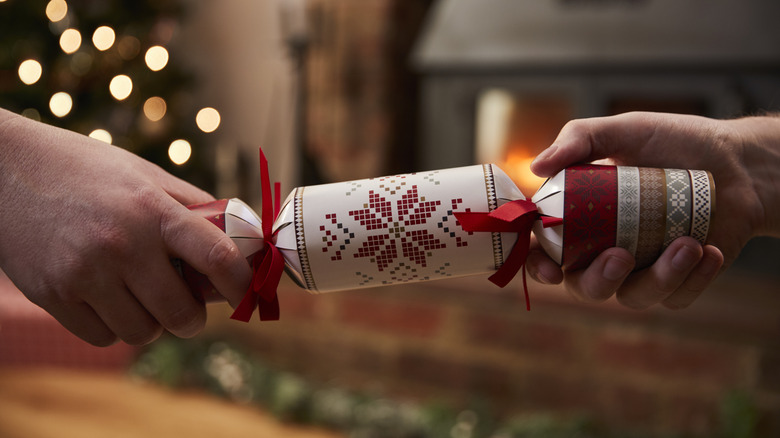 Two hands holding opposite ends of a Christmas cracker