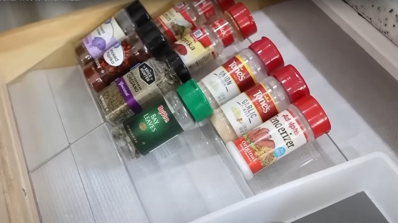 Spices angled on a plastic picture frame in kitchen drawer