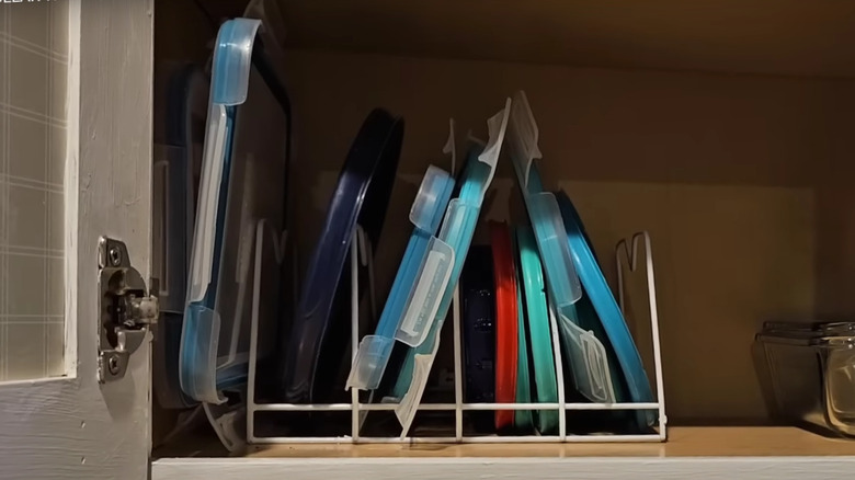 Assorted Tupperware lids on dollar store drying rack in cabinet
