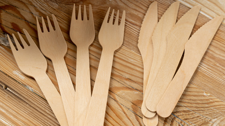 Disposable green utensils on a wooden surface