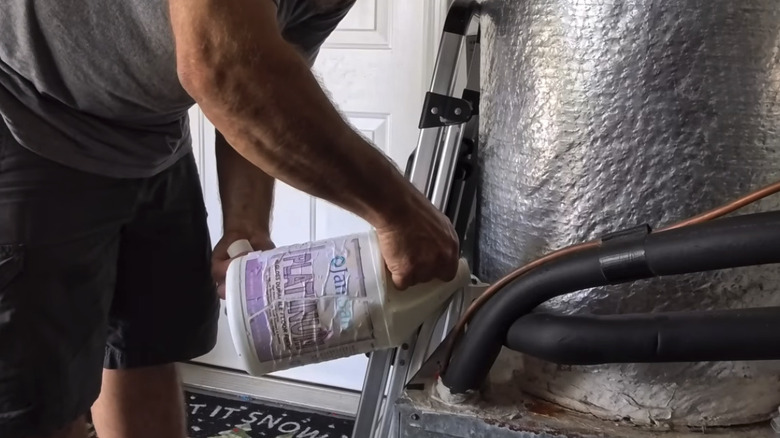 A man pouring liquid into the drain line of an air conditioning system