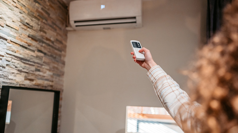 Close-up of a person switching off an air conditioner with a remote control