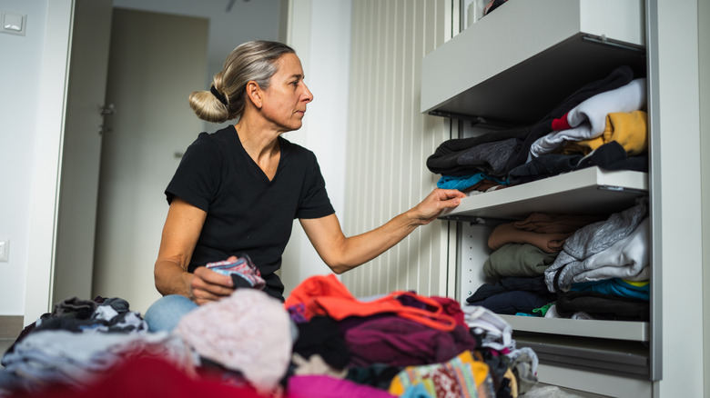 A person sitting on the floor and organizing a pile of clothes