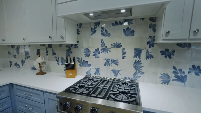 A kitchen backsplash with white and blue painted tiles.