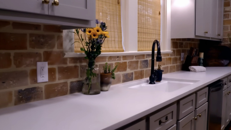 A modern sink and countertop with a brick backsplash.