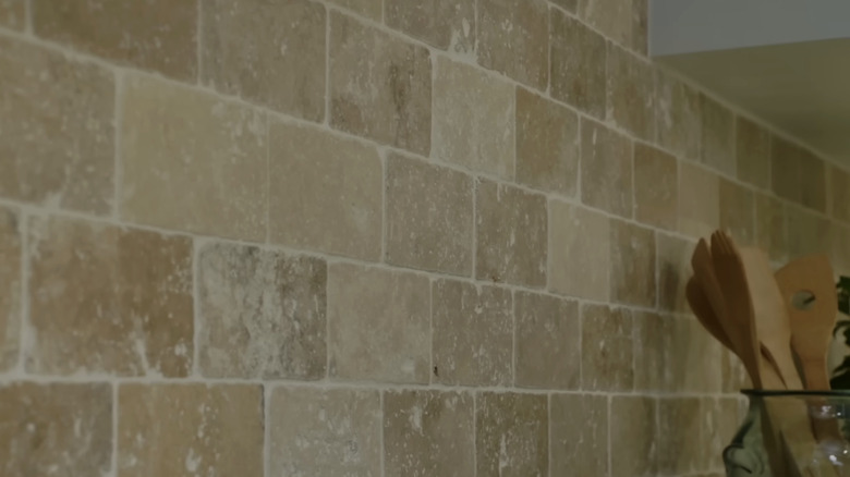 A close-up of a travertine tile backsplash.