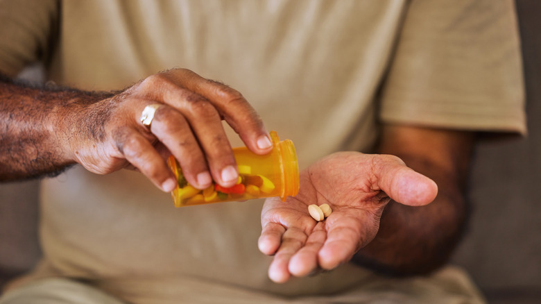 Older man pouring pills out of an orange bottle into his hand