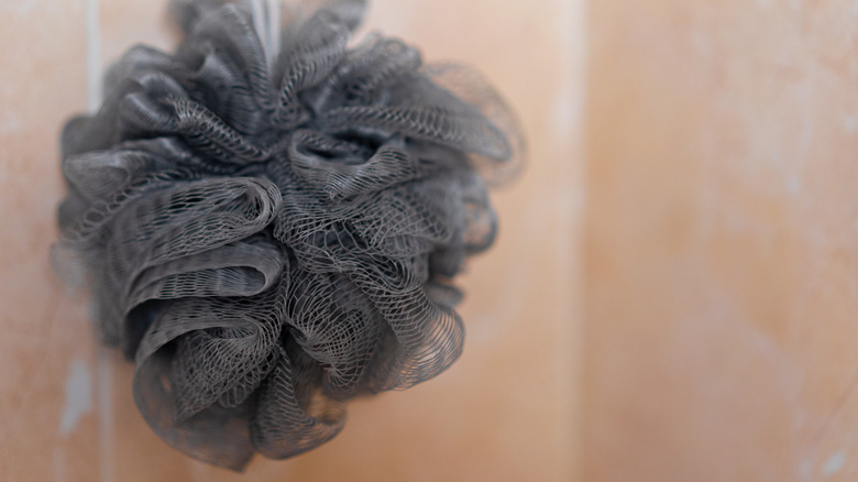 A gray synthetic loofah hangs in a shower stall.