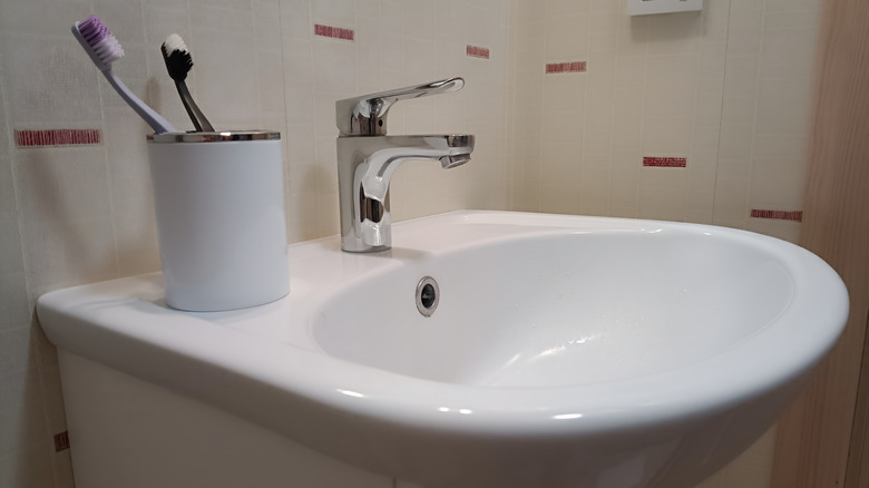 A white plastic toothbrush holder on a bathroom sink.