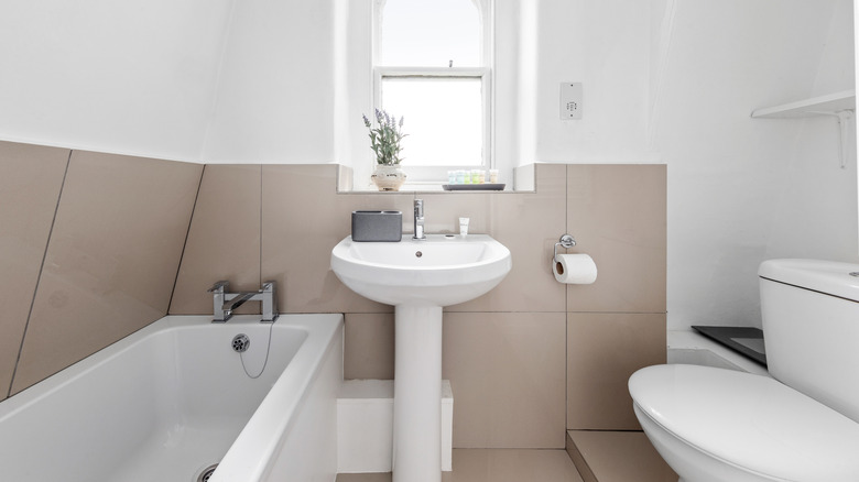 Small bathroom with tan tile, white walls and white pedestal sink