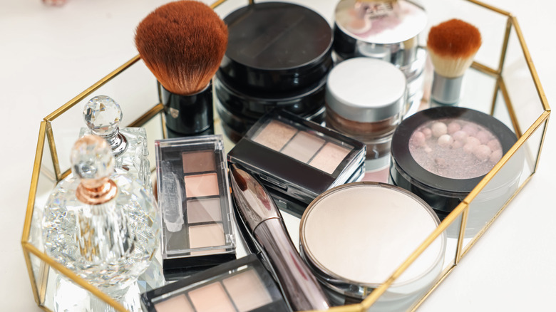 A mirrored gold makeup tray with used products.