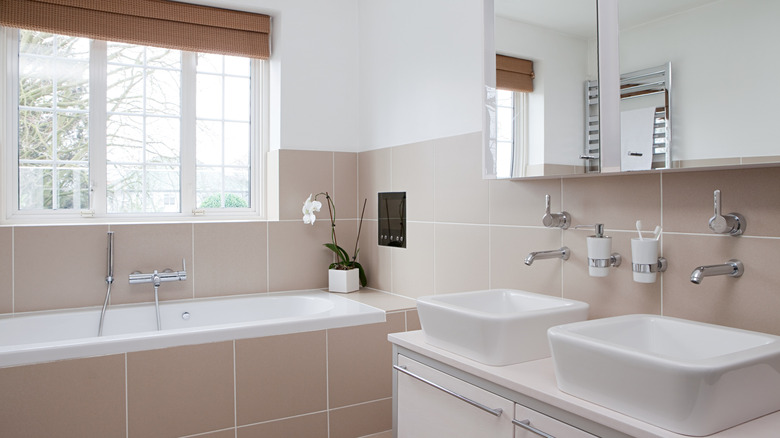 A minimalist bathroom with beige tile and built-in tub