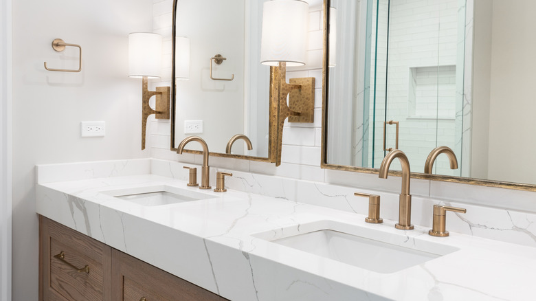 A modern bathroom with marble countertops and brass hardware.