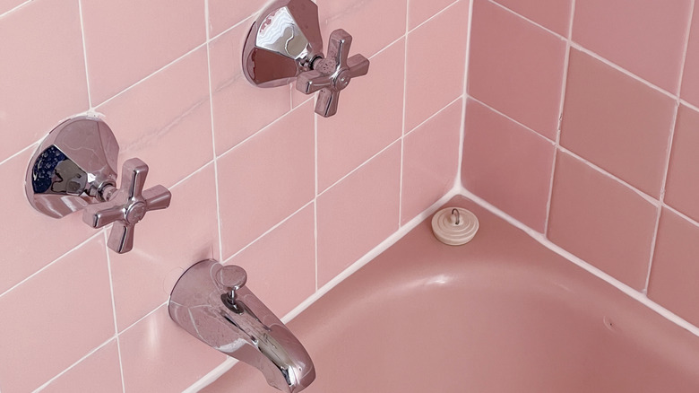 A close-up on a pink-tiled tub.