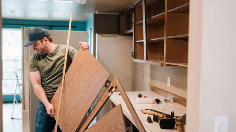 Man removing upper cabinets in a kitchen