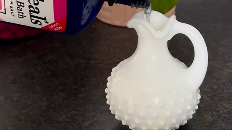 Pouring bubble bath in a milk glass cruet oil bottle