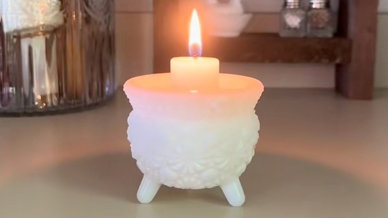Milk glass footed cauldron with a lit candle inside
